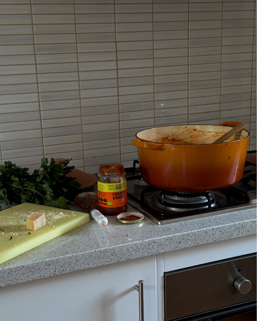 Orange pot on a stove with ingredients to make a pasta