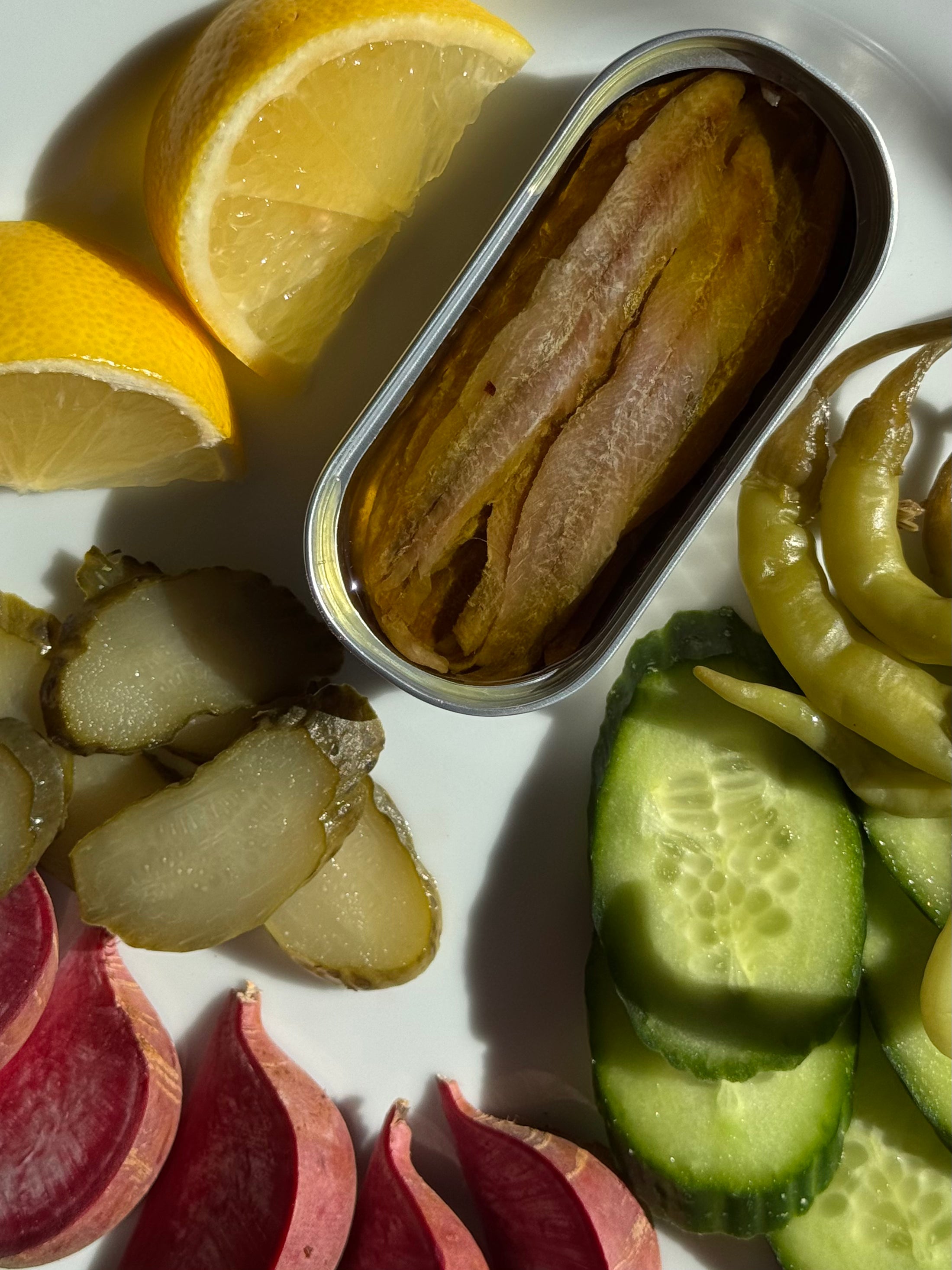Assorted salad & vegetables next to an open tin of anchovies