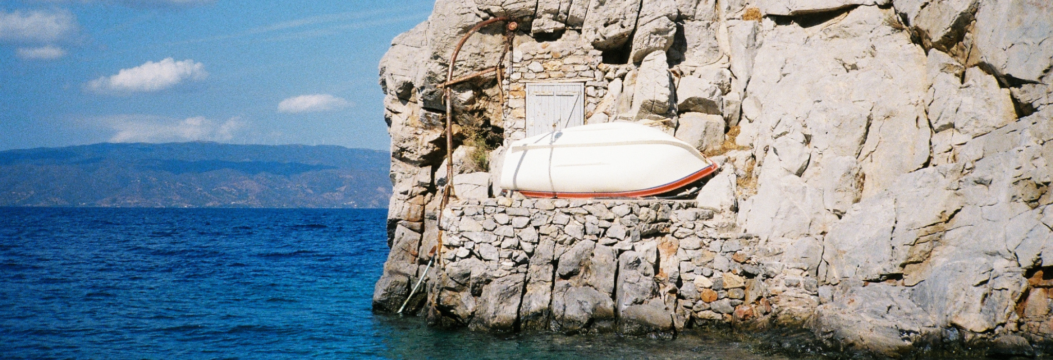Rocky coastal scene with a small boat resting above the water.
